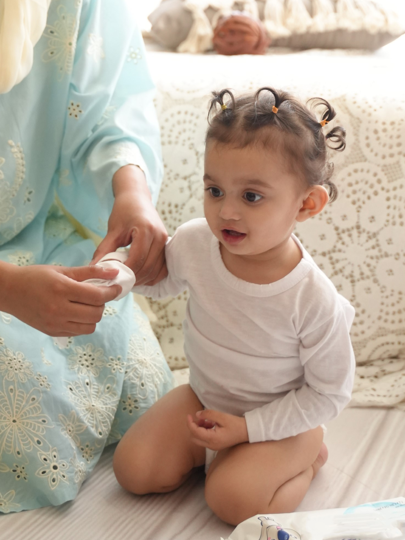 Mother wiping hands with wipes for her cute baby girl.