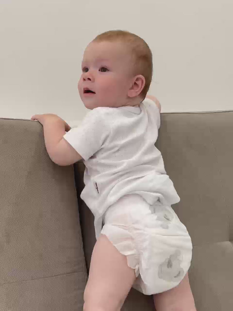 The video shows an infant moving around on the couch wearing an Aiwibi Ultimate Comfort Disposable Overnight.